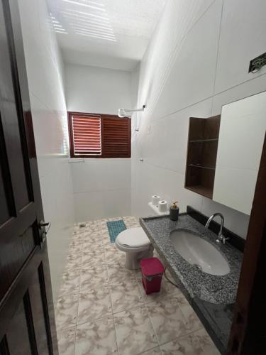 a white bathroom with a toilet and a sink at Casa em FRENTE À PRAIA, ao lado do Nord Hotel - Tabatinga in Conde