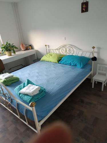 uma cama com lençóis azuis e almofadas verdes num quarto em Apartma pri Renati em Celje