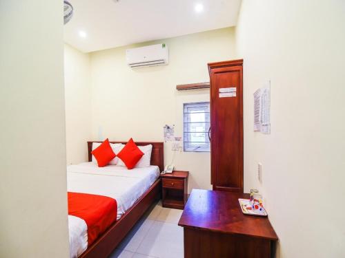 a bedroom with a bed with red pillows and a desk at Hùng Thư Motel in Da Nang