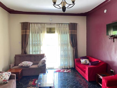 a living room with red furniture and a window at Pearl Sanctuary 02_Kisoro Homestay in Kisoro