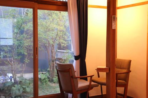 a room with a window with a chair and a table at Hostel Fish in a River in Takayama
