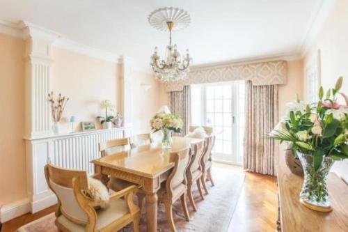 comedor con mesa, sillas y lámpara de araña en Cheerful 3 bedroom house with generous rear garden en Kent