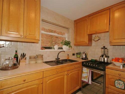 a kitchen with wooden cabinets and a sink at Cheerful 3 bedroom house with generous rear garden in Kent