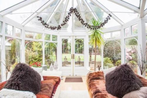 a conservatory with a couch in a room with windows at Cheerful 3 bedroom house with generous rear garden in Kent