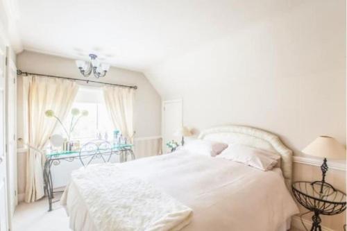 a white bedroom with a bed and a window at Cheerful 3 bedroom house with generous rear garden in Kent