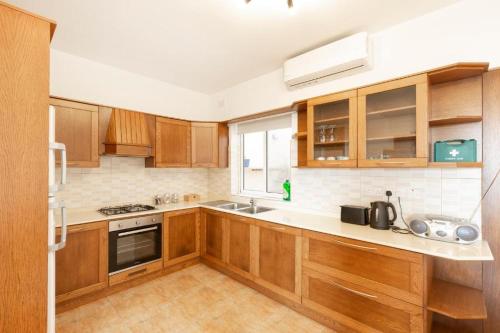 una cocina con armarios de madera y fregadero en Gudja - Lovely 3 bedroom unit with own private entrance en Gudja