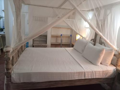 a bedroom with a canopy bed with white pillows at Sophia house in Malindi