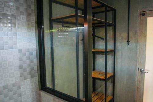 a shower with a glass shelf in a bathroom at Uma Dewa homestay in Keramas