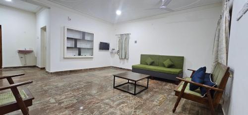 a living room with a green couch and a table at HOMESTAY - AC 3 BHK NEAR AlRPORT in Chennai