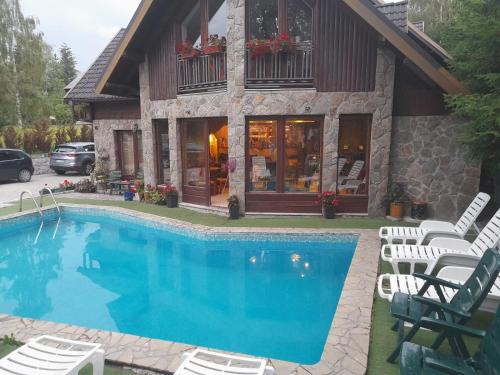 uma piscina em frente a uma casa com cadeiras e um edifício em Vila Zlatibor em Zlatibor