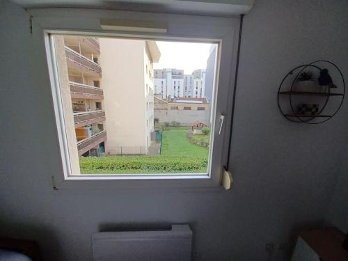 - une fenêtre dans une salle de bains avec vue sur un bâtiment dans l'établissement Appartement 2 personnes Lyon Sans Souci, à Lyon
