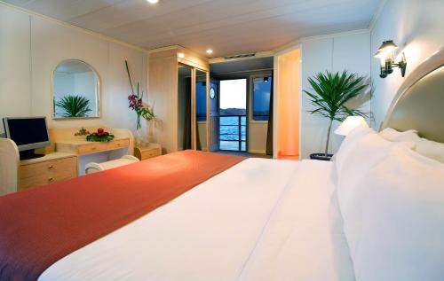 a bedroom with a large white bed and a television at Mövenpick Prince Abbas Lake Nasser Cruise, Every Monday Four Nights From Aswan, Every Friday Three nights From Abu-Simbel - Including Excursions and Sightseeing in Aswan