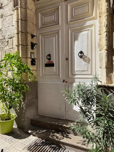 a white door on a building with some plants at Valletta Private Room in Valletta
