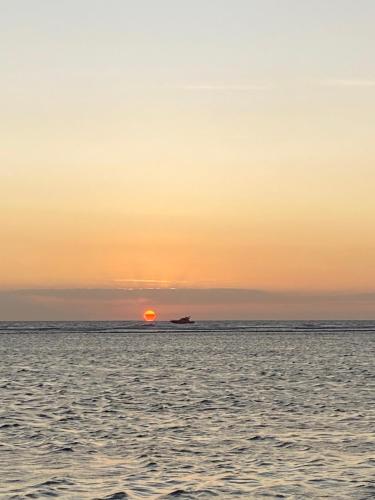a boat in the ocean with the sunset in the background at Gili pelangi in Mataram