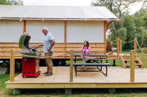 a man and a woman standing on a deck with a house at Battenkill Glamping Resort in Cambridge