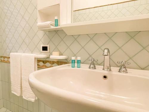 La salle de bains est pourvue d'un lavabo, d'un miroir et de serviettes. dans l'établissement Brain Loft Pagani, à Pagani