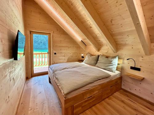 1 dormitorio en una cabaña de madera con cama y ventana en Das Grünhaus - Dein Chalet in Grünau im Almtal en Grünau im Almtal