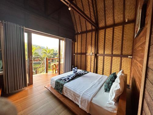 ein Schlafzimmer mit einem Bett in einem Zimmer mit einem großen Fenster in der Unterkunft Lake Batur Cottage in Bangli