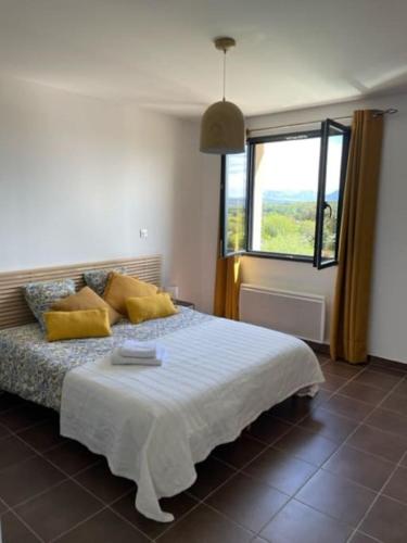 Un dormitorio con una cama con almohadas amarillas y una ventana en Maison avec terrasse proche Grignan en Colonzelle