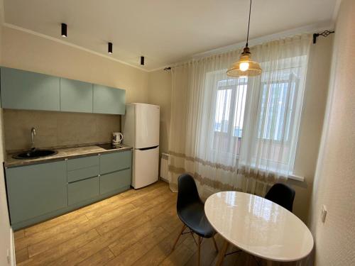 Il comprend une cuisine équipée d'une table et d'un réfrigérateur blanc. dans l'établissement Apartament LETO, à Astana