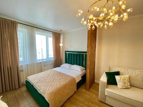 - une chambre avec un lit, une chaise et un lustre dans l'établissement Apartament LETO, à Astana