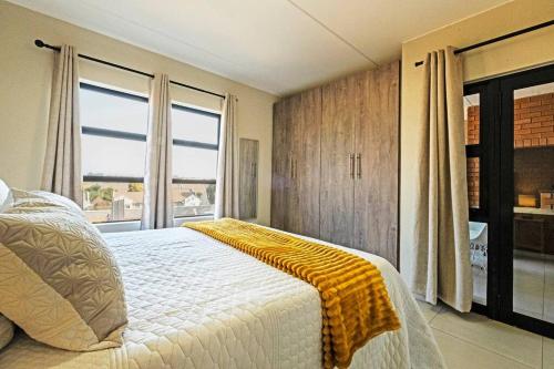 a bedroom with a bed with a yellow blanket on it at Airport Heights II in Boksburg