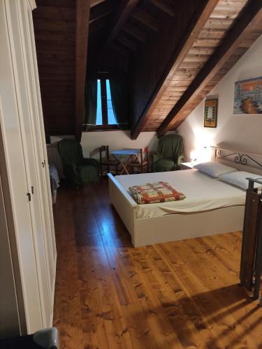1 dormitorio con cama blanca y suelo de madera en La dimora delle corti, en Vanzone