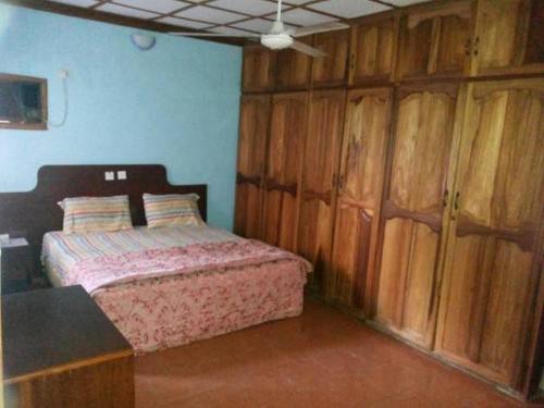 1 dormitorio con 1 cama y armarios de madera en Room in Lodge - Garentiti Apartment - Silver Room, en Iyiba