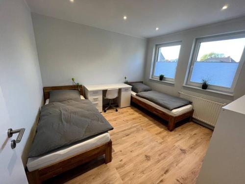 1 Schlafzimmer mit 2 Betten, einem Schreibtisch und 2 Fenstern in der Unterkunft Ferienwohnung am Glockensee in Bad Laer