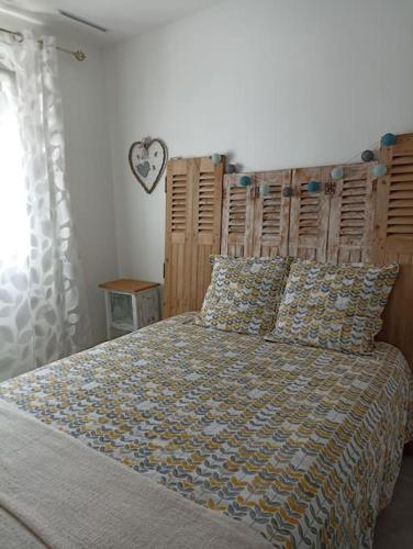 une chambre avec un grand lit avec une tête de lit en bois dans l'établissement Maison d'hôtes cosy & agréable à 5min du Futuroscope, à Saint-Georges-lès-Baillargeaux