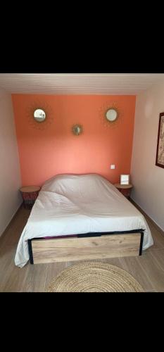 Studio du Quintinet في Le Quillio: سرير في غرفة بجدار برتقالي