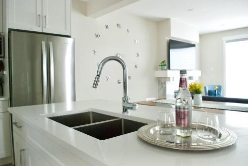 a kitchen with a sink and a stainless steel refrigerator at Modern Altadore Home 3 Br Fireplace Sleeps 8 in Calgary