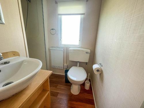 uma casa de banho com um lavatório, um WC e uma janela. em Lovely 6 Berth Caravan At Skipsea Sands Park In Yorkshire Ref 41053sf em Barmston