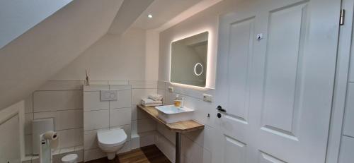 Baño blanco con lavabo y aseo en Gemütliche Wohnung am Wald 