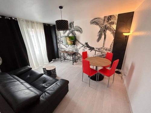 - un salon avec un canapé en cuir noir et des fauteuils rouges dans l'établissement Esprit Panthère, à Mulhouse