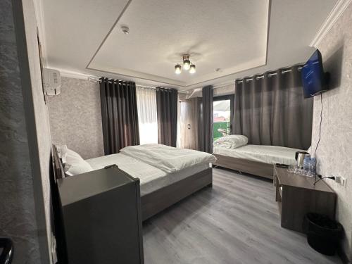 ein Schlafzimmer mit 2 Betten und einem TV. in der Unterkunft Byond Hotel & Hostel in Taschkent