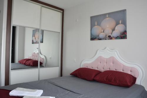 1 dormitorio con cama con almohadas rojas y espejo en Hera Emlak en Kırac