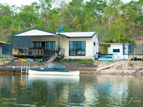 a house on the water with a boat in front of it at Bungalow 58 in Lake Bennett
