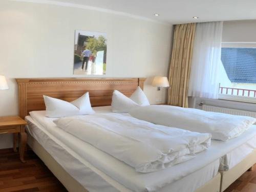 a large white bed with white sheets and pillows at Landidyll Hotel Restaurant Weidenbrück & SPA in Swisttal