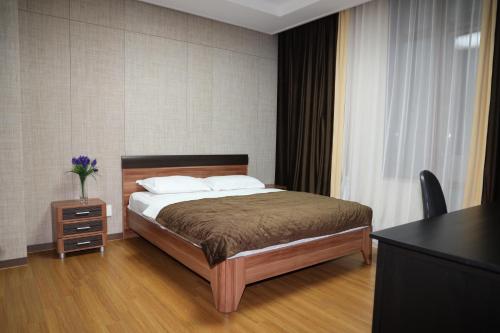 a bedroom with a bed and a table and a window at Highvill Apartments in Astana