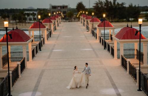 uma noiva e um noivo a caminhar num cais em Tiinder Hotel em Xuyên Mộc