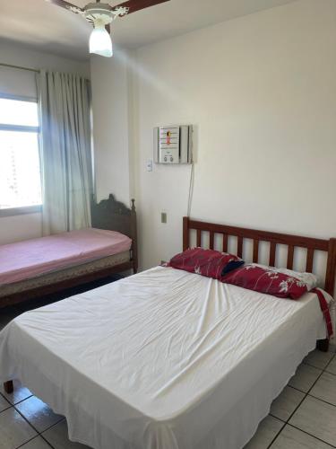 Un dormitorio con una gran cama blanca y una ventana en Apartamento Guarapari pé na areia com Wi-Fi e Garagem en Guarapari