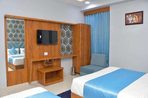 a hotel room with a bed and a tv and a chair at Hotel Green Park in Gandhinagar