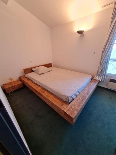 um quarto com uma cama de madeira num quarto com uma janela em Villa "Les Flots en Ré" em La Flotte