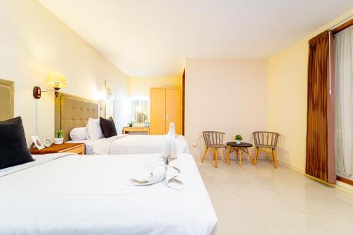 um quarto de hotel com duas camas e uma mesa e cadeiras em Payu Hotel Jogja em Jetis