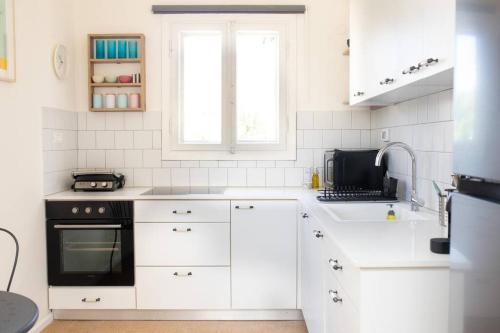 a white kitchen with a sink and a stove at lovely apartment in Ra'anana in Ra‘ananna