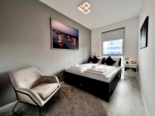 ein Schlafzimmer mit einem Bett und einem Stuhl in der Unterkunft SuiteAngel - Luxury Design Condo with free garage in Budapest