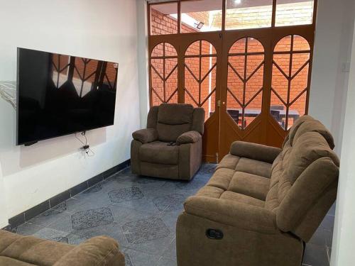 Casa Hospedaje Cajamarca في كاخاماركا: غرفة معيشة مع كنبتين وتلفزيون بشاشة مسطحة