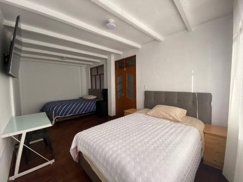 a bedroom with a bed and a desk and a television at Casa Hospedaje Cajamarca in Cajamarca