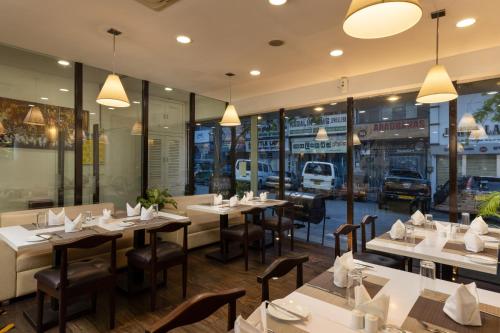 a restaurant with tables and chairs and windows at Cafe Aroma Inn in Kandy